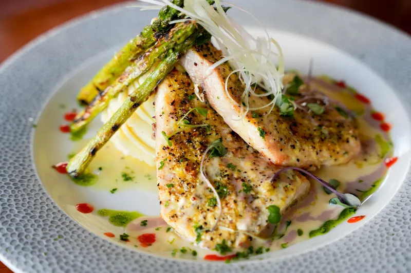 A crusted fish fillet plated with asparagus